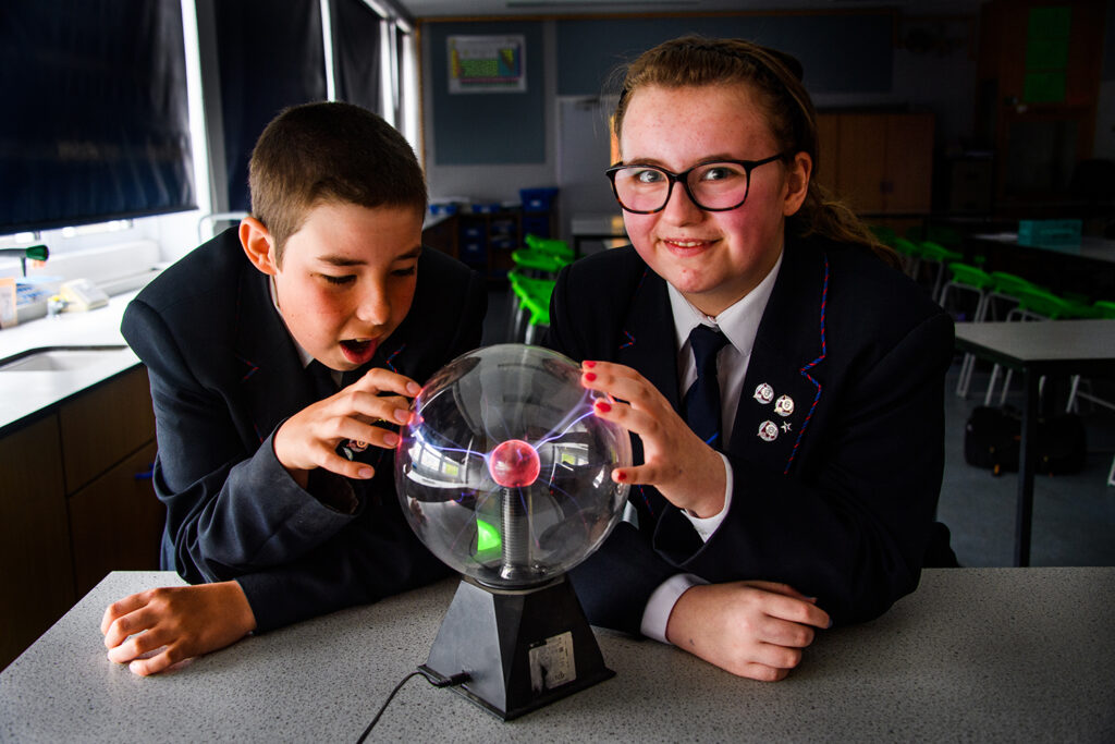Male and female student touching a plasma ball