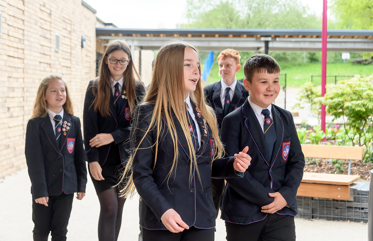 Five students conversing as they walk through school grounds 2