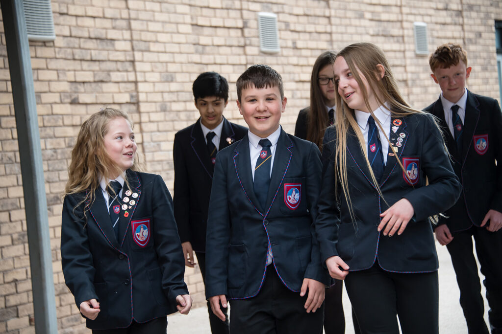 Five students conversing as they walk through school grounds