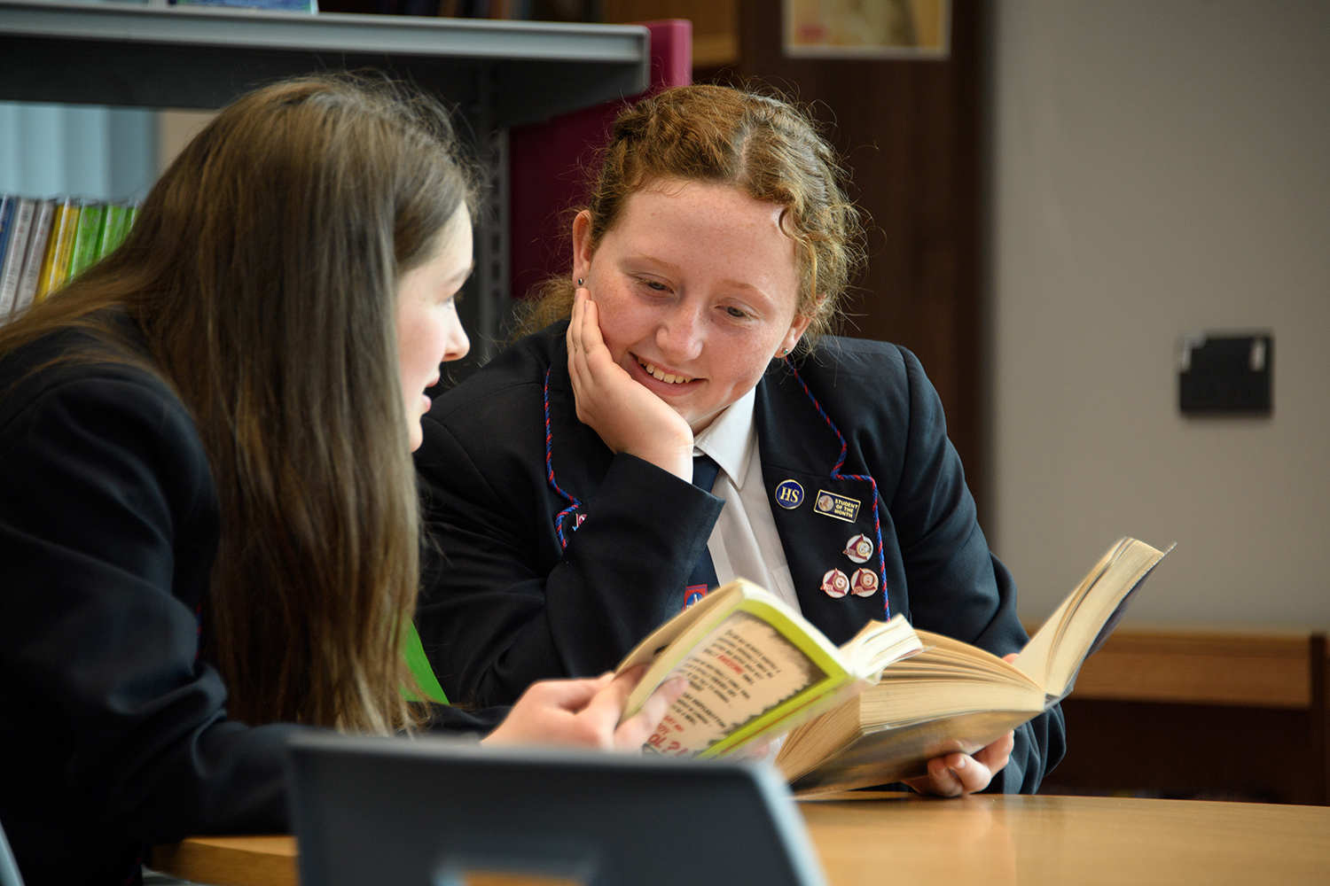 Two girls reading together in library