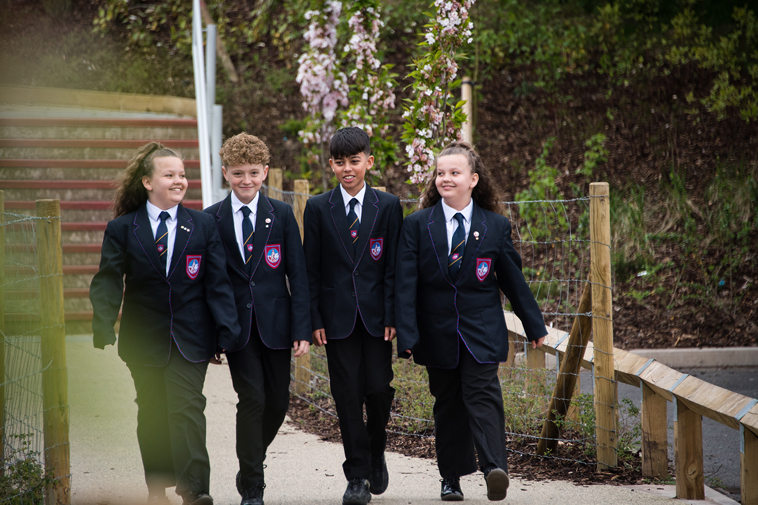 Four students smiling walking through school grounds