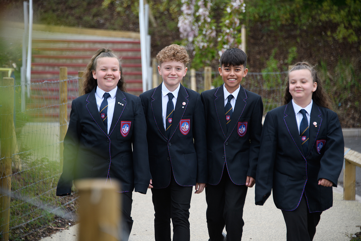 Four students smiling walking through school grounds