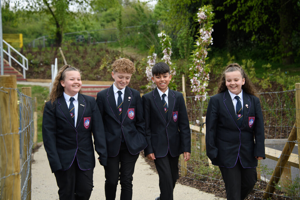 Four students smiling walking through school grounds