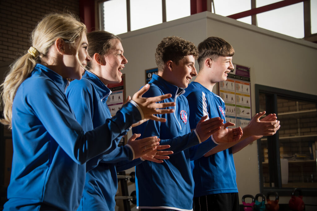 Four PE students clapping and laughing