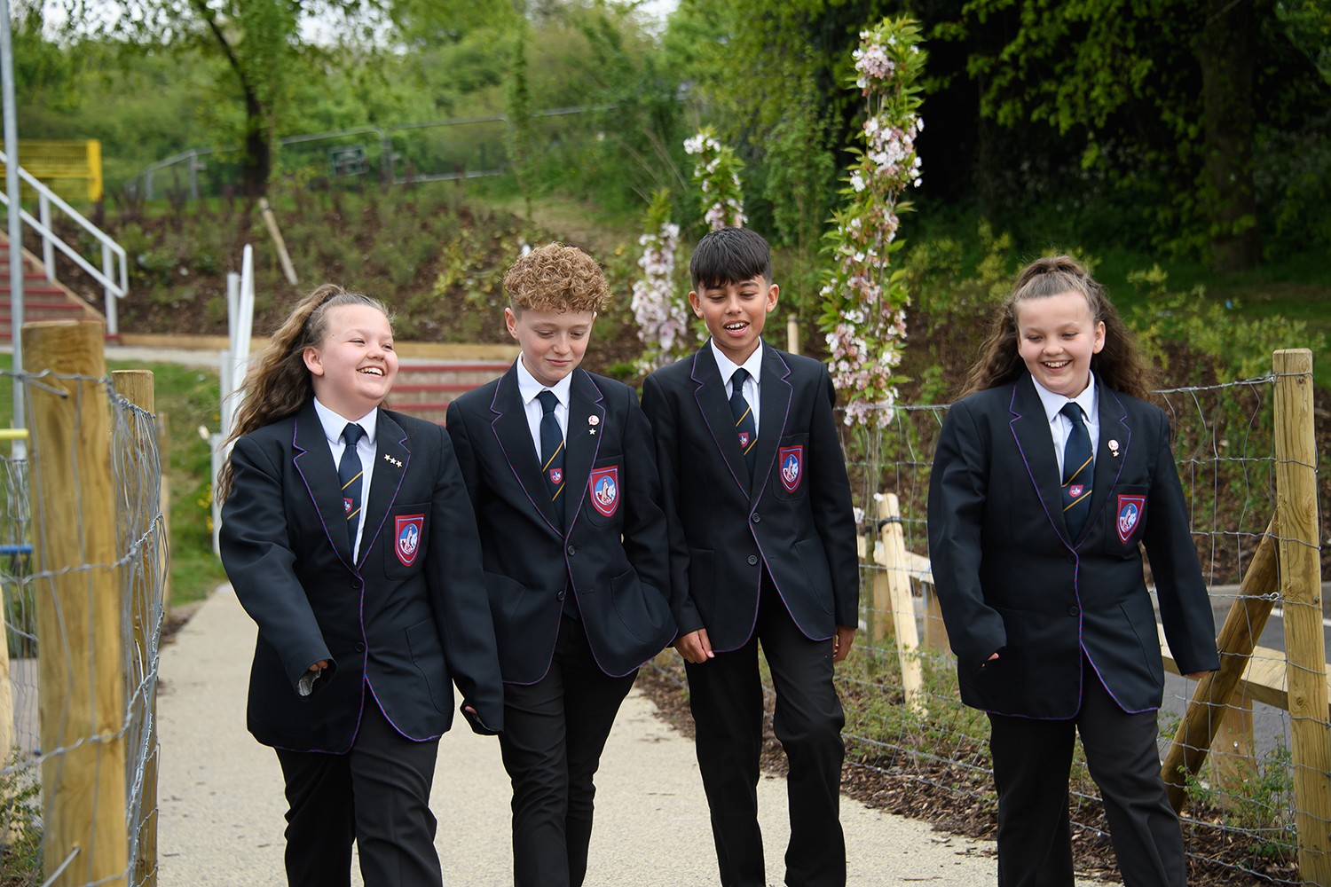 Four students talking and smiling while walking through the school grounds