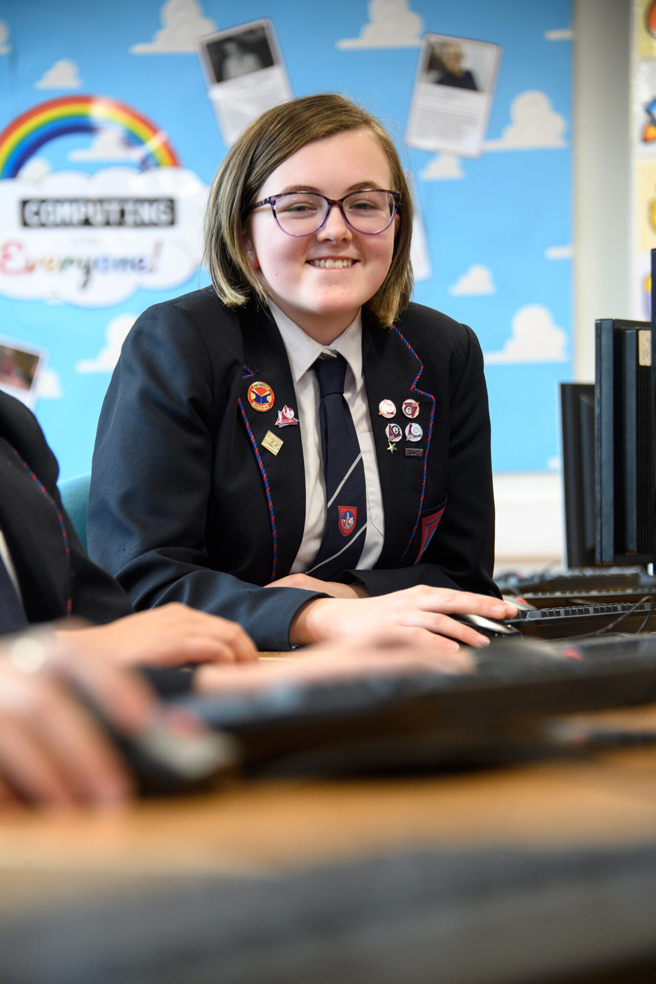 Girl smiling at the camera, sitting in computer room