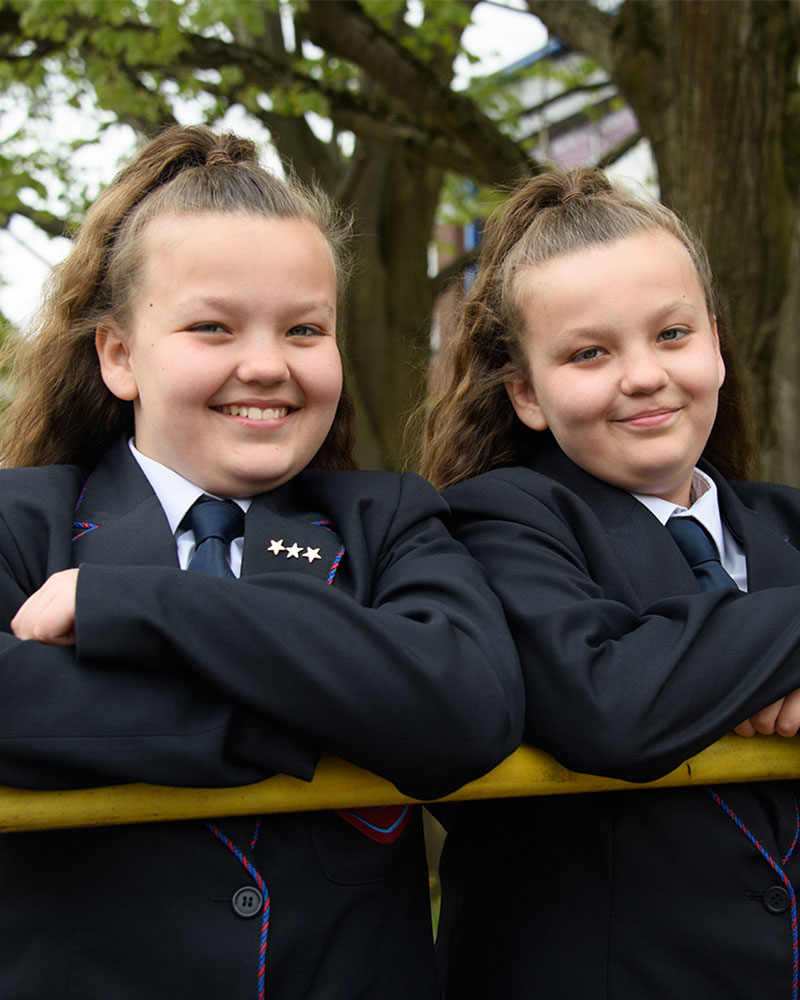 Twin students smiling on school grounds