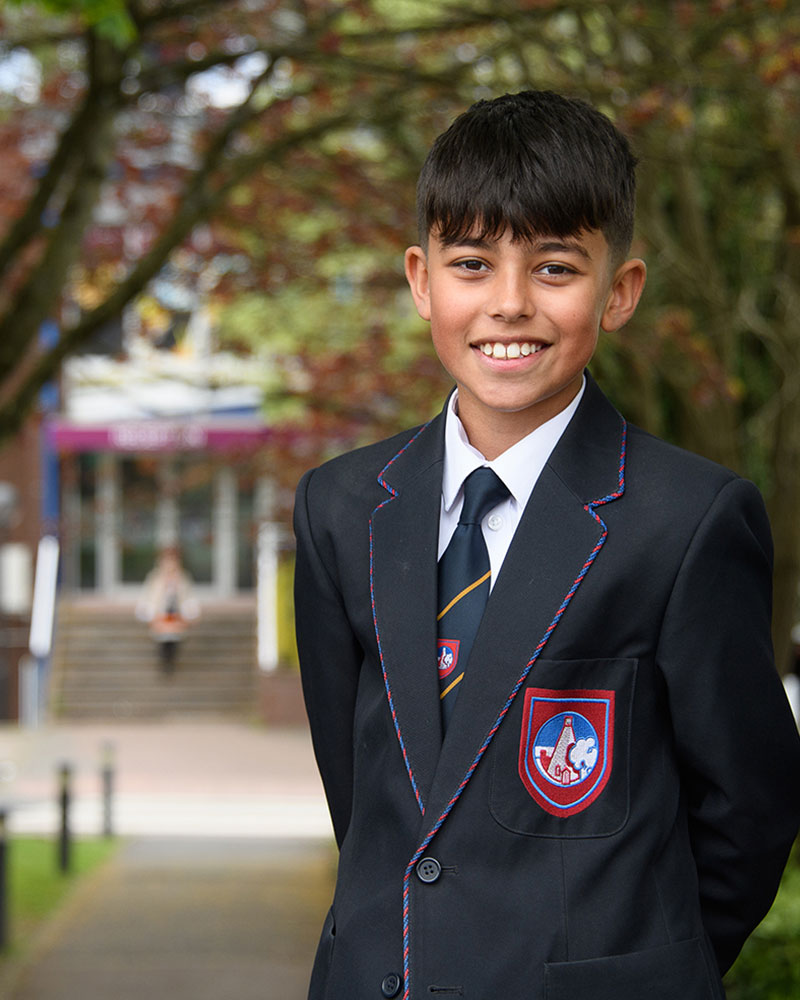 Boy smiling in front of school entrance