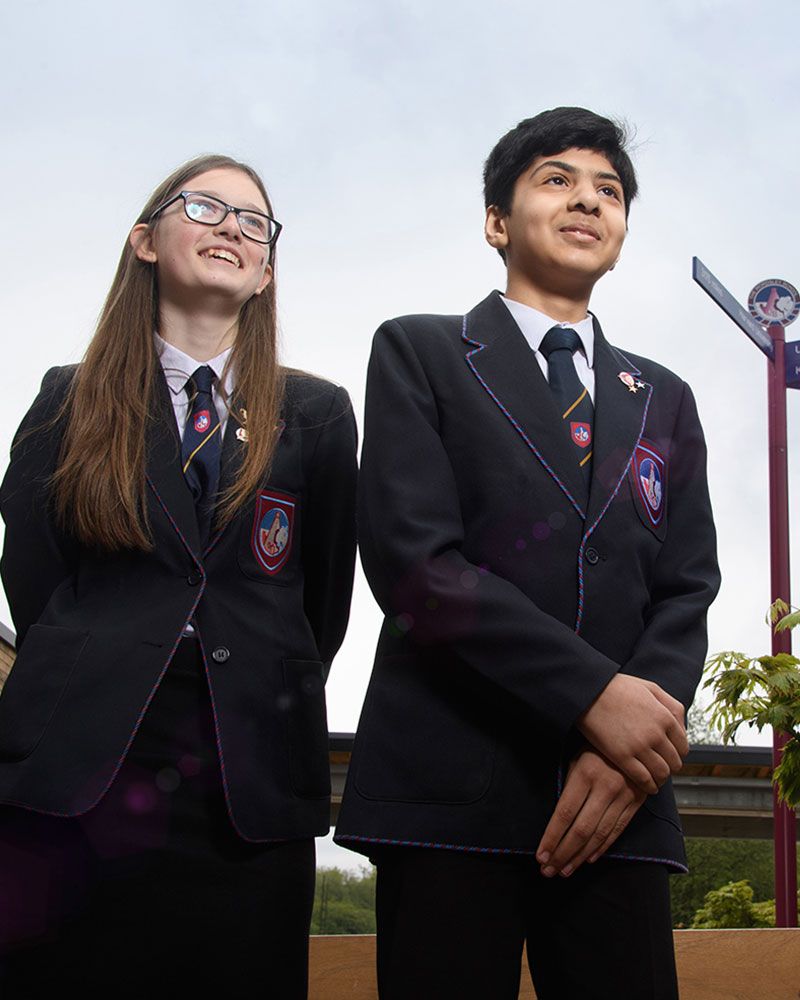 Two students smiling in front of Wordsley direction signpost